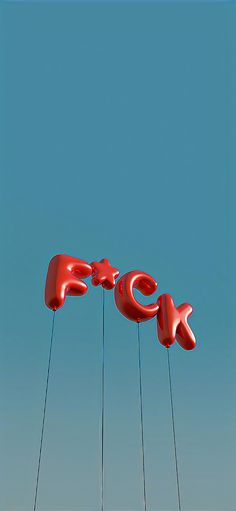 two red letters are suspended from strings in the air with blue sky behind them and one is upside down