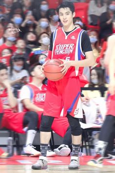 a young man holding a basketball while standing on top of a basketball court in front of an audience