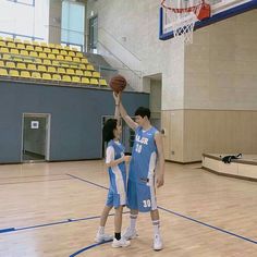 two young men playing basketball on an indoor court