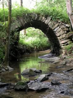 a stone bridge over a stream in the woods