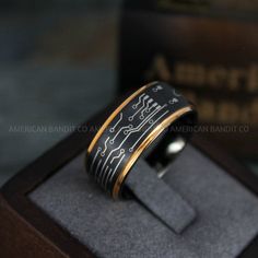 a black and gold ring with an electronic circuit printed on the side in a wooden box