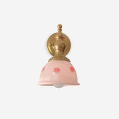 a pink and gold light hanging from a ceiling fixture with flowers on it's side