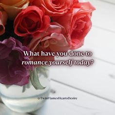 a vase filled with lots of pink and orange flowers on top of a white table