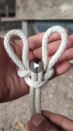 a person holding a white rope with a knot on it's end and an object in the background