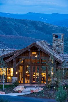 a large house in the middle of a mountain range at night with lights on it's windows