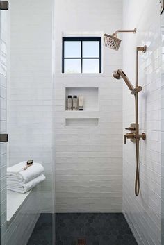 a white tiled bathroom with black flooring and shower head mounted to the side of the wall