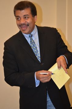 a man in a suit holding a notepad and pen