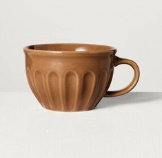 a brown coffee cup sitting on top of a white table