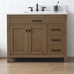 a bathroom vanity with two sinks and wood cabinetry on the side, in front of a white wall