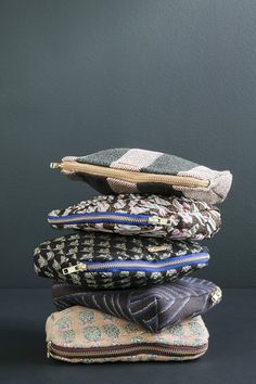 five different colored zippered pouches stacked on top of each other in front of a black wall