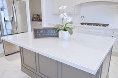 a kitchen counter with a sign that says mom's kitchen on it and a potted plant in the middle