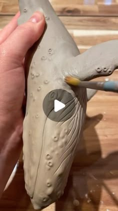 a person is holding a clay whale in their hand