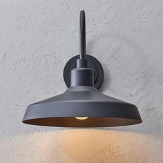 a light that is on the wall next to a white wall with a gray shade