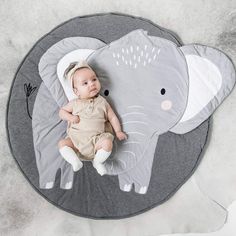 a baby laying on top of an elephant rug