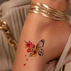 a woman's arm with a butterfly and flowers tattoo on the left side of her arm