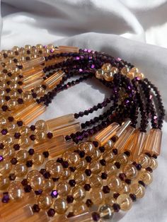 Why You'll Love It: Striking Design: The rich purple crystal glass beads paired with the warm golden sandy brown accents create a luxurious and timeless aesthetic. Premium Quality: Crafted with high-quality glass beads, ensuring durability and lasting brilliance. Comfortable Fit: The elastic design offers a comfortable and flexible fit for all-day wear. Versatile Style: Perfect for everyday wear, special occasions, or as a thoughtful gift. Cultural Significance: Purple: In Ivorian culture, purpl Elegant Glass Crystal Necklaces For Party, Amber Beaded Jewelry For Party, Brown Faceted Beads Jewelry For Party, Elegant Beaded Glass Crystal Necklace, Elegant Amber Beaded Necklaces With Large Beads, Elegant Glass Beaded Necklaces For Parties, Elegant Glass Beaded Necklace With Round Beads, Elegant Adjustable Brown Crystal Necklaces, Purple Jewelry With Gold Beads For Party