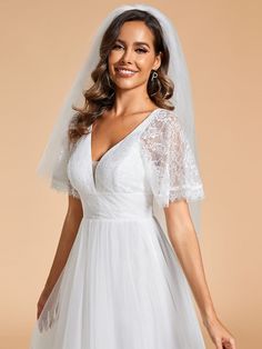 a woman wearing a white wedding dress with a veil on her head and smiling at the camera