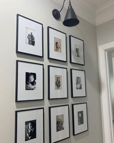 a white wall with black and white pictures hanging on it's side next to a lamp