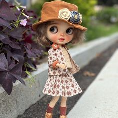 a small doll wearing a brown hat and dress