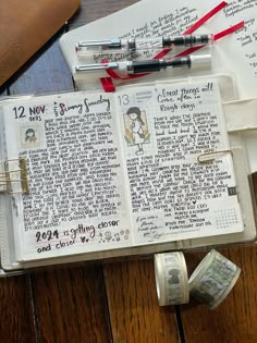 an open bible on a wooden table with some money and pens in front of it