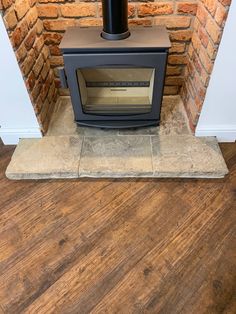 a wood burning stove sitting inside of a brick fireplace