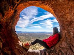 a woman sitting on top of a rock formation