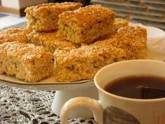 several pieces of food on a plate next to a cup of coffee and some cookies