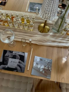 a wooden table topped with lots of bottles and glasses next to an empty glass vase