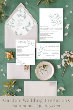 the wedding stationery is laid out on a green surface with white flowers and greenery