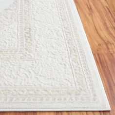 a white area rug on the floor with wood floors and hard wood planks in the background