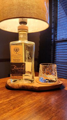 a bottle of whisky sitting on top of a wooden table next to a glass cup