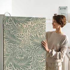 a woman is holding up a wallpaper in the kitchen