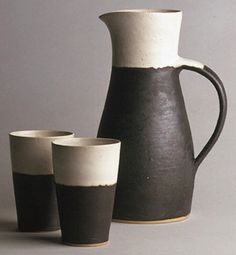 three black and white vases sitting next to each other in front of a gray background