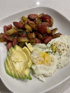 an egg, potatoes and avocado on a white plate