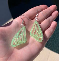 Each pair of earrings are made to order, therefore no two pairs are identical! However, I try to get as close as possible :) Made with resin & chunky iridescent baby lime glitter (UV/Blacklight reactive)✨  Color may vary slightly. Thanks for visiting my shop! 🦋 Other color options are available in my shop! Green Fairy Earrings For Gift, Fairy Style Green Earrings For Gifts, Handmade Fairy Earrings For Party, Unique Green Butterfly Earrings, Handmade Fairy Drop Earrings, Handmade Fairy Style Drop Earrings, Whimsical Green Hypoallergenic Earrings, Handmade Green Fairy Jewelry, Green Fairy Wings