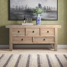 a wooden dresser sitting in front of a painting on the wall next to a rug