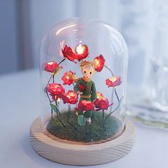 a small figurine under a glass dome with flowers