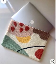 an apple laptop computer sitting on top of a white table next to a bath mat