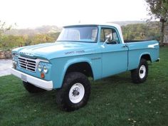 an old blue pick up truck parked in the grass