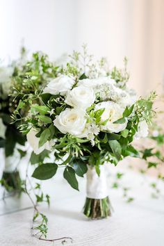 two vases filled with white flowers and greenery