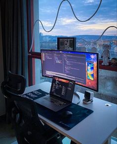 a laptop computer sitting on top of a desk in front of a monitor and keyboard