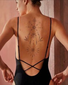 the back of a woman's body wearing a black swimsuit with an intricate tattoo