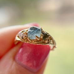 a close up of a person's hand holding a ring with a stone in it