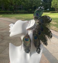 a white mannequin with peacock feathers on it's head and earring