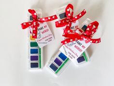 three different colors of paint are tied to each other with red ribbons and tags on them