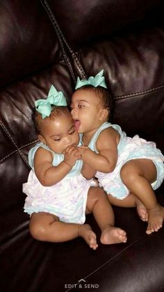 two babies sitting next to each other on top of a brown leather couch with their mouths open