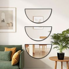 a living room with three mirrors on the wall and a potted plant next to it