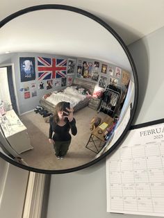 a woman taking a selfie in the mirror with her cell phone and calendar on the wall