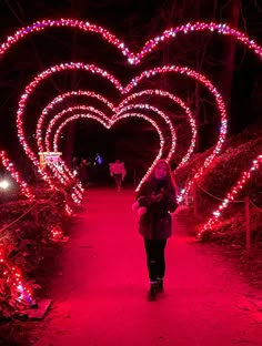 a woman walking down a path with lots of lights in the shape of hearts on it