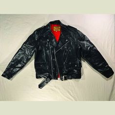 Rare Milano made in Japan faux leather punk jacket. Overall jacket is in excellent condition. Outer material is incredibly durable and supple, with no visible marks or tears. The jacket features waist belt, cuffs with zippers as well as button snaps, three front pockets lined in soft fabric, and lower back studded detail. The interior lining is an incredibly bright cherry red, with a small visible stain (shown in last image). Brand: Milano Tagged Size: M Material: Faux Leather Made in: Japan * Measurements taken laying flat* armpit to armpit: 22" middle of neckline to cuff: 34 1/2" middle of neckline to hem: 28 1/2" KEEP IN MIND: This jacket may be over 30 years old, and like with any vintage items there is minor wear. I do my best to find, disclose, and photograph imperfections and includ Rocker Leather Outerwear For Alternative Fashion, Biker Style Leather Outerwear For Alternative Fashion, Punk Red Biker Jacket For Biker Events, Red Punk Biker Jacket For Biker Events, Red Leather Punk Outerwear, Punk Style Leather Jacket For Concerts, Punk Leather Jacket For Concerts, Winter Rockabilly Outerwear For Streetwear, Vintage Red Leather Biker Jacket